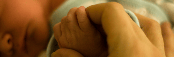 Photo of mother clutching newborn baby's hand